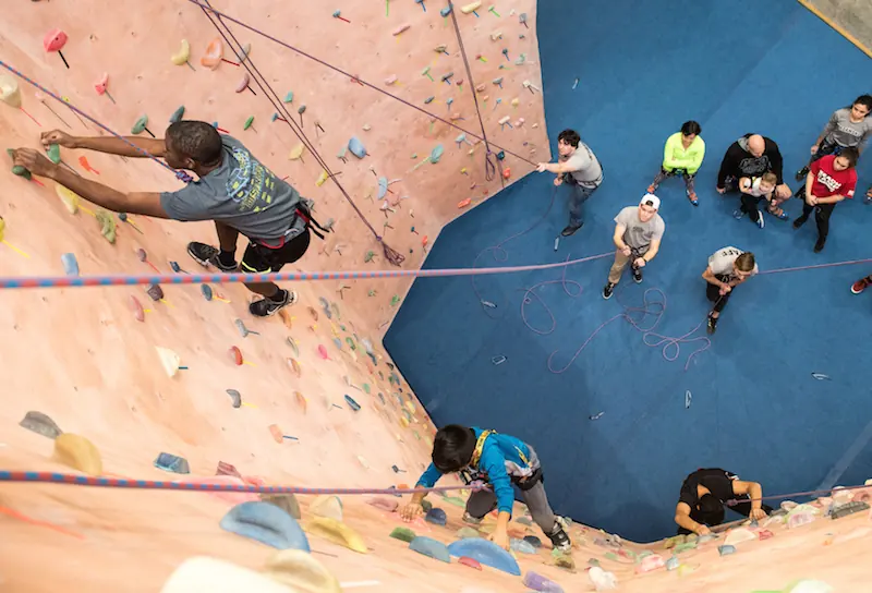 Looking down a roped wall at a climber and belayers below